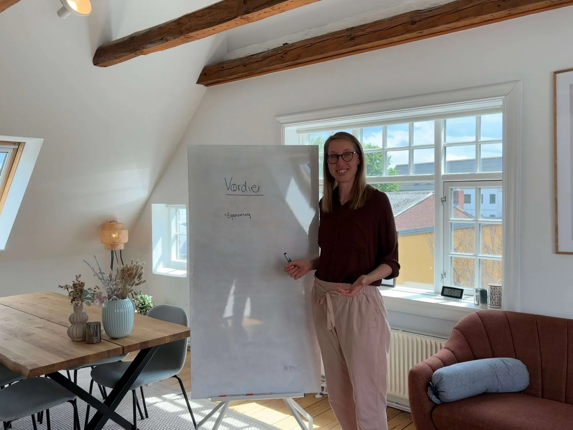 Enkelt, lyst rum med en stol, et lavt bord og en potteplante